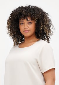 Beige short-sleeve top with a round neckline, made from textured fabric. Smooth silhouette and relaxed fit.