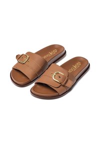 Braune Leder-Sandalen mit breitem Riemen, der eine goldfarbene Schnalle trägt, und einem glatten Fußbett, auf einer dunkelbraunen Sohle.