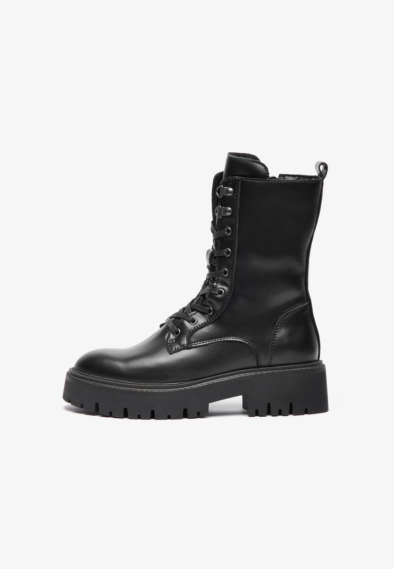 Botte de combat en cuir noir avec une texture lisse, avant à lacets, détails cousus et semelle crantée épaisse. Équipée d'une languette à l'arrière.