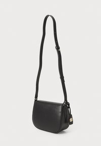 Borsa a spalla in pelle nera con forma curva, tracolla regolabile, dettagli in hardware dorato e un'etichetta piccola attaccata.