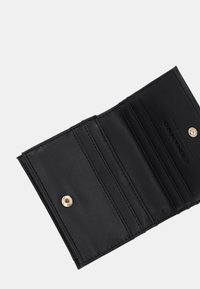 Portafoglio in pelle nera con quattro scomparti per carte, trama liscia, chiusura a scatto dorata e marchio impresso sul lato interno.