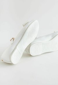 Ballerine bianche in satin liscio, decorate con un piccolo fiocco e una suola texturizzata con motivi floreali.