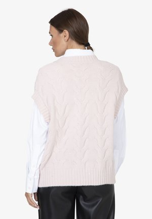 Lichtroze gebreide vest met een kabelpatroon, geribbelde halslijn en korte mouwen, gedragen over een wit shirt. Bevat subtiele glansdetails.