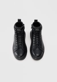 Zapatillas altas negras de cuero, con superficie texturizada, cierre de cordones en la parte frontal y una tira de sujeción en el tobillo con detalle de logo.