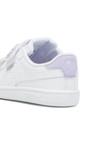 Baskets blanches avec une tige en cuir lisse, des accents violets, un collier rembourré et une semelle extérieure texturée avec un logo sur le côté et le talon.