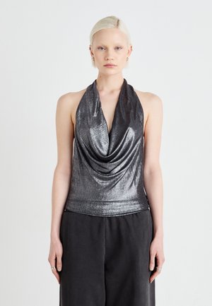 Metalni srebrni halter top s drapiranim izrezom, uskim dizajnom, glatkom teksturom i minimalističkim stilom, uparen s tamnim širokim hlačama.