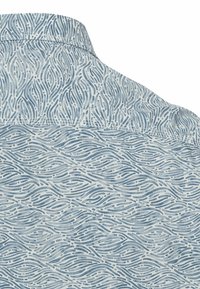 Camisa con estampado que presenta un diseño de olas azul claro sobre un fondo blanco, confeccionada en una tela suave con una textura lisa.