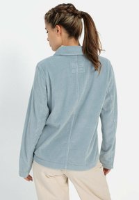 Lichtblauw corduroy overhemd met lange mouwen, een kraag en een gestructureerd patroon. Bevat een decoratieve patch op de achterkant van de schouder.