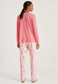 Roze lange mouwen top met een ronde hals, gecombineerd met roze pyjamabroekjes met een speelse dierenprint. Zacht, lichtgewicht materiaal.