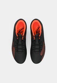 Črne športne čevlje z teksturirano površino, ki imajo svetlo oranžne poudarke, vezalke in perforirane detajle na zgornjem delu.