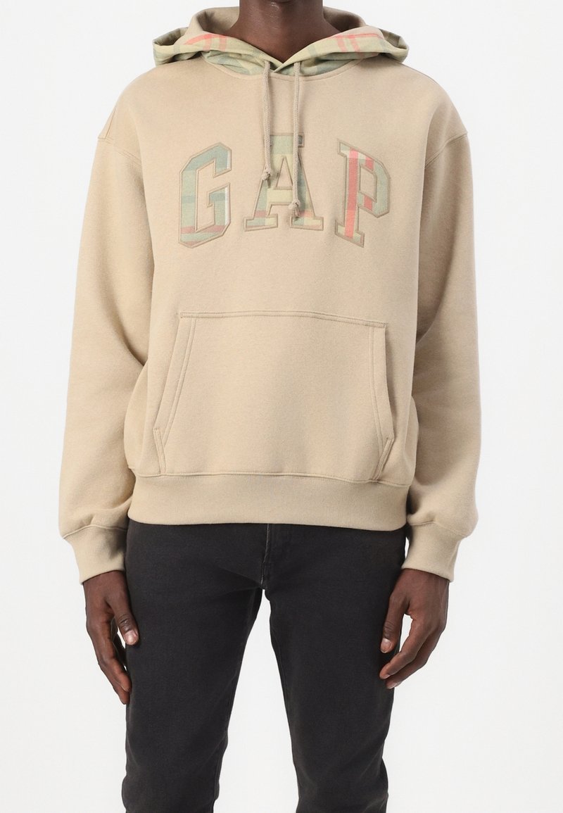 Beżowa bluza z kapturem z logo "GAP" w kolorowych blokowych literach, wyposażona w kaptur ze sznurkiem i kieszeń kangur, wykonana z miękkiej bawełnianej dzianiny mieszanej.