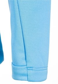 Lichtblauwe sportbroek van rekbare stof, met een taps toelopende pasvorm en een gestikte zoomafwerking. Gladde textuur, geen patronen.