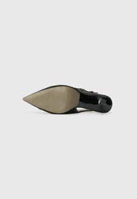 Schwarzer High-Heel-Schuh mit spitzem Zeh, glänzendem Lackfinish und strukturierter Stoffverarbeitung an der Ferse und den Seiten. Gummisohle mit Rippung.