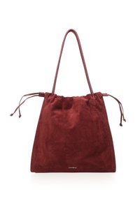Suède draagtas met trekkoord in diep bordeauxrood. Zachte textuur, verlengde bandjes en subtiele branding onderaan. Simpele, ongestructureerde vorm.
