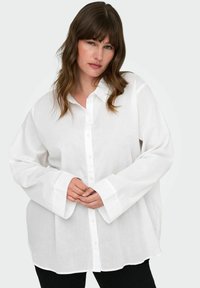Camicia bianca con bottoni realizzata in tessuto leggero. Presenta maniche lunghe con polsini larghi e un colletto classico. Vestibilità casual e rilassata.