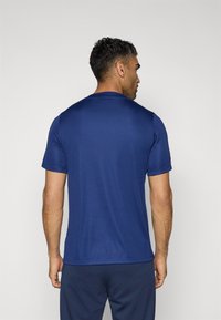 Marineblå atletisk t-shirt med korte ermer og rund halsudskæring, med en glat tekstur og en afslappet pasform, set bagfra.