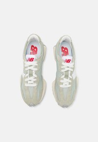 Sneakers v světle zelené a béžové barvě s materiály z semiše a síťoviny, mají bílé tkaničky a červené logo na jazyku a stélce.