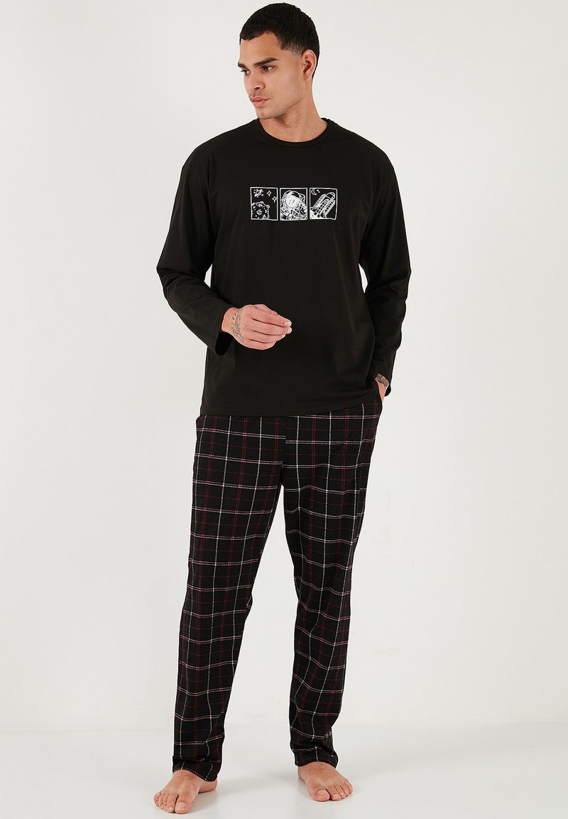Camisa negra de manga larga con diseños gráficos y pantalones a cuadros en tonos negros, blancos y rojos; tejido suave con un corte relajado.