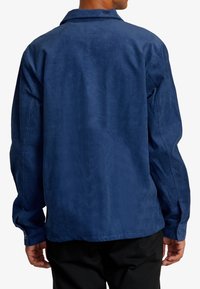 Camicia in velluto a coste blu navy con maniche lunghe, polsini abbottonati e colletto a punta; presenta una texture a coste verticali e una vestibilità rilassata.
