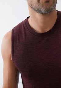 Μαρούλι αμάνικο αθλητικό μπλουζάκι με στρογγυλή λαιμόκοψη, που διαθέτει υφή και ανάγλυφο σχέδιο. Κοντινή λήψη που αναδεικνύει την περιοχή του ώμου και του λαιμού.