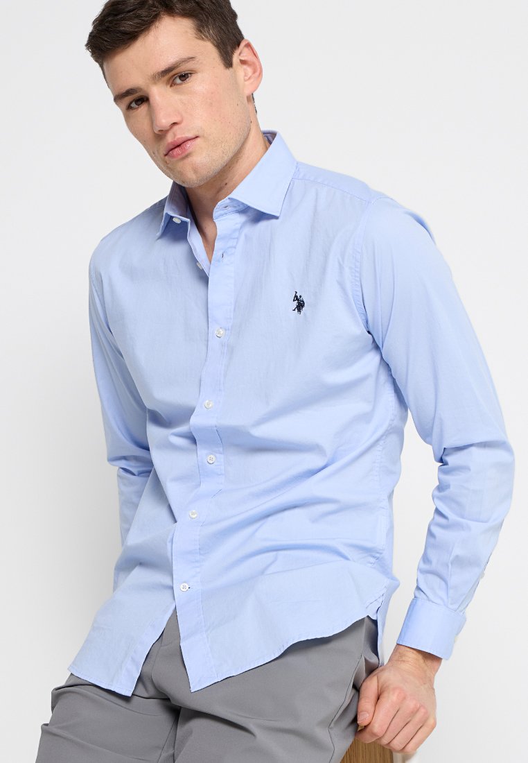 Camicia a maniche lunghe azzurro chiaro in morbido cotone, con colletto a punta e piccolo logo scuro sul lato sinistro del petto.