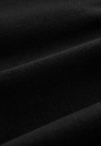 Schwarzer Baumwollstoff mit glatter Textur, der subtile Variationen in Farbton und Tiefe aufweist und eine matte Oberfläche zeigt.