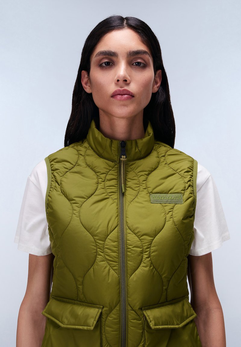 Kurtka kamizelka w oliwkowym kolorze z pikowaną fakturą, wysokim kołnierzem, zamkiem z przodu i dwiema kieszeniami z przodu. Posiada subtelne logo oraz wyrazistą, wyściełaną konstrukcję.