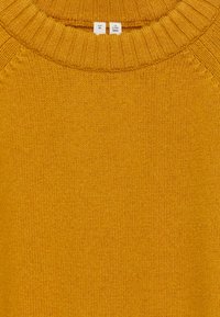 Senfgelbes Strickpullover mit geripptem Rundhalsausschnitt und glatter Textur. Etiketten zeigen die Größe M und Pflegehinweise an.