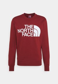 Felpa bordeaux a maniche lunghe con collo rotondo, con polsini e orlo a costine, caratterizzata dal grande logo bianco "THE NORTH FACE" sul davanti.