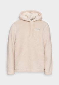 Hoodie en polaire beige et duveteux avec une capuche à cordon de serrage, arborant un petit logo sur le haut à gauche de la poitrine et des poignets côtelés. Texture douce.