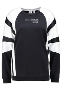 Svart och vit sweatshirt med långa raglanärmar, som har en rund halsringning, sportiga ränder och texten "EQUIPMENT" på bröstet.
