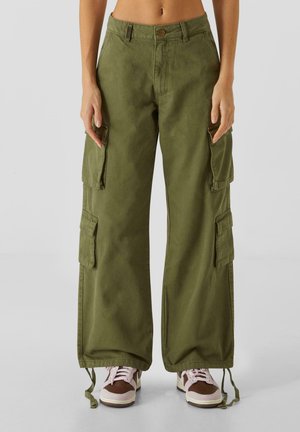 Pantaloni cargo in verde oliva, realizzati in tessuto resistente. Caratterizzati da gambe ampie, numerose tasche laterali e stringhe regolabili all'orlo.