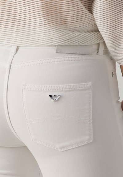 Valged denim teksad, mille tagakotil on väike metallist logo. Omab klassikalist viie tasku disaini ja peeneid õmblusdetailide.