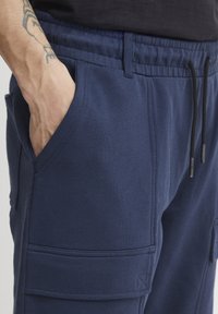 Pantalons de jogging en coton bleu marine avec une taille élastique et des cordons de serrage, dotés de poches latérales et de détails de couture visibles.