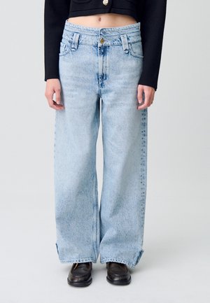 Jeans a gamba larga di colore blu chiaro con vita alta, dotati di tasche anteriori e chiusura a bottone. Il tessuto presenta una texture in denim consumato.