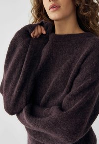 Pulover violet închis cu o textură moale și pufoasă, umeri căzuți și mâneci lungi, cu un decolteu larg și o croială lejeră.