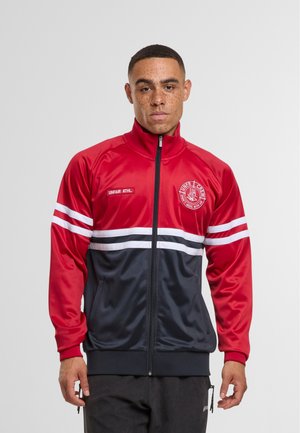 Rode en marineblauwe zip-up trainingsjas van glanzend materiaal. Kenmerkt zich door witte strepen op de mouwen en een logo op de borst. Elastische manchetten en zoom.