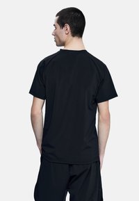 Camiseta deportiva negra de manga corta y corte relajado, hecha de una tela suave y ligera, con un diseño liso sin patrones.