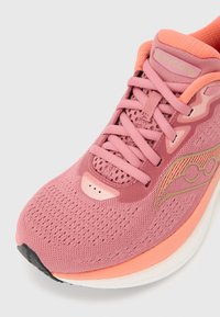 Ροζ και κοραλλί αθλητικό παπούτσι Saucony με επάνω μέρος από δίχτυ, κλείσιμο με κορδόνια, μαλακό γιακά και λευκή σόλα με μαύρη άκρη στα δάχτυλα.