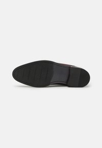 Suela de zapato de cuero marrón con una suela de goma negra texturizada que presenta un patrón hexagonal, puntera redondeada y tacón acampanado.