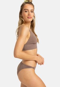 Brūns ribots bikini komplekts ar sporta stila topu ar platiem siksnām un atbilstošiem zema vidukļa apakšveļām. Gluda tekstūra, minimālisma dizains.