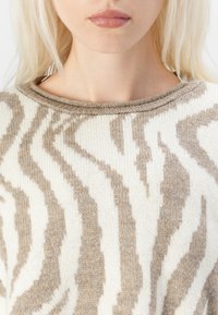 Beige and cream striped knit sweater with a round neckline and textured pattern, featuring soft fabric and subtle color variations.
