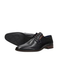 Zwarte leren dresschoenen met een spitse neus, afgewerkt met een textuur van gaas en een bruine detaillering bij de enkel. Vlakke rubberen zool met profielpatroon.