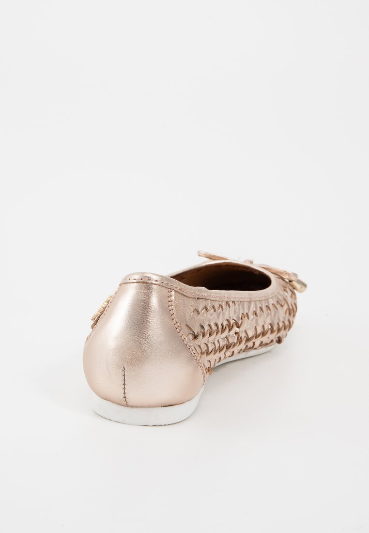 Botte plate en rose doré métallique avec texture tissée, bout arrondi et un accent en nœud à l'avant. Talon lisse avec semelle extérieure blanche.