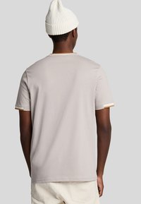 T-shirt grigio chiaro a maniche corte con colletto rotondo e finiture a contrasto color sabbia sulle maniche, realizzato in morbido tessuto di cotone.