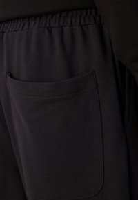 Schwarze Jogginghosen mit seitlichem Taschen, elastischem Taillenbund, weicher Stofftextur und figurbetontem Design für Komfort.