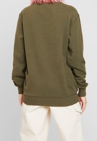 Olive green oversized sweatshirt with long sleeves, ribbed cuffs and hem, and soft cotton material. Simple design, no patterns or accents.
