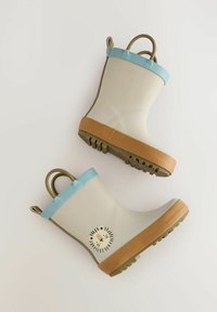 Bottes de pluie en caoutchouc blanches avec des bordures bleu clair, semelle marron et un graphique de lion sur le côté. Équipées de poignées doubles pour un enfilage facile. Fond plat et texturé.