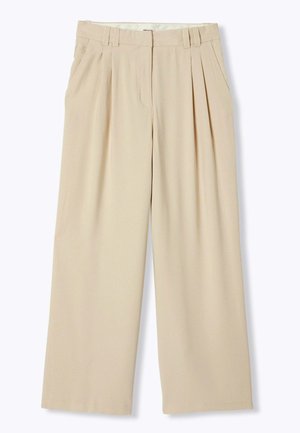 Pantalon beige à jambes larges avec plis devant, poches latérales, passants pour ceinture et fermeture frontale dissimulée.