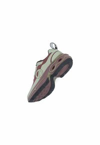 Sneaker met een gebogen ontwerp, voorzien van een lichtgroene bovenkant, bordeauxrode accenten, zwarte rand en een getextureerde rubberen zool met ronde grips.